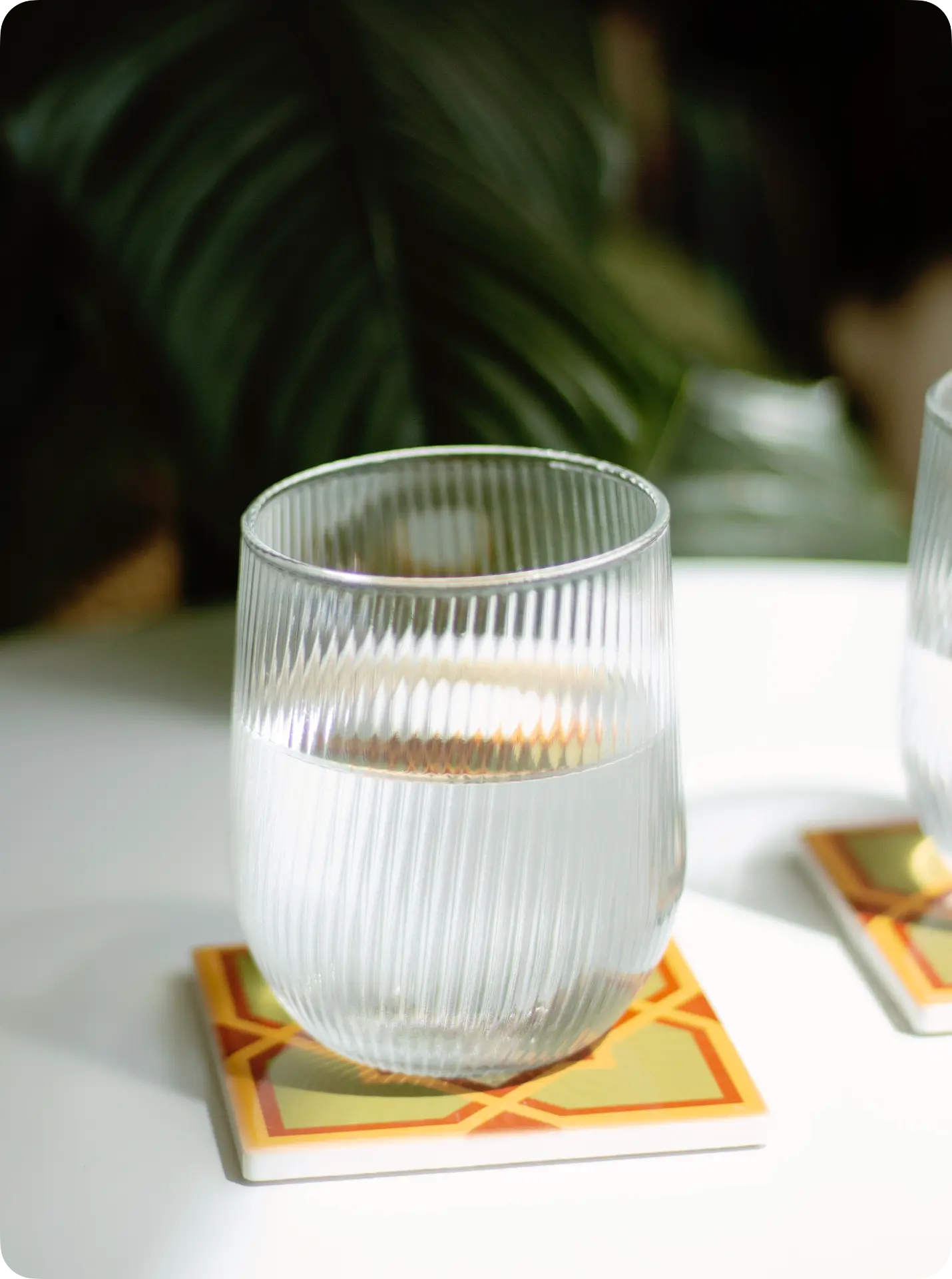 Vaso de vidrio estriado sobre un posavasos PisoVaso amarillo y naranja